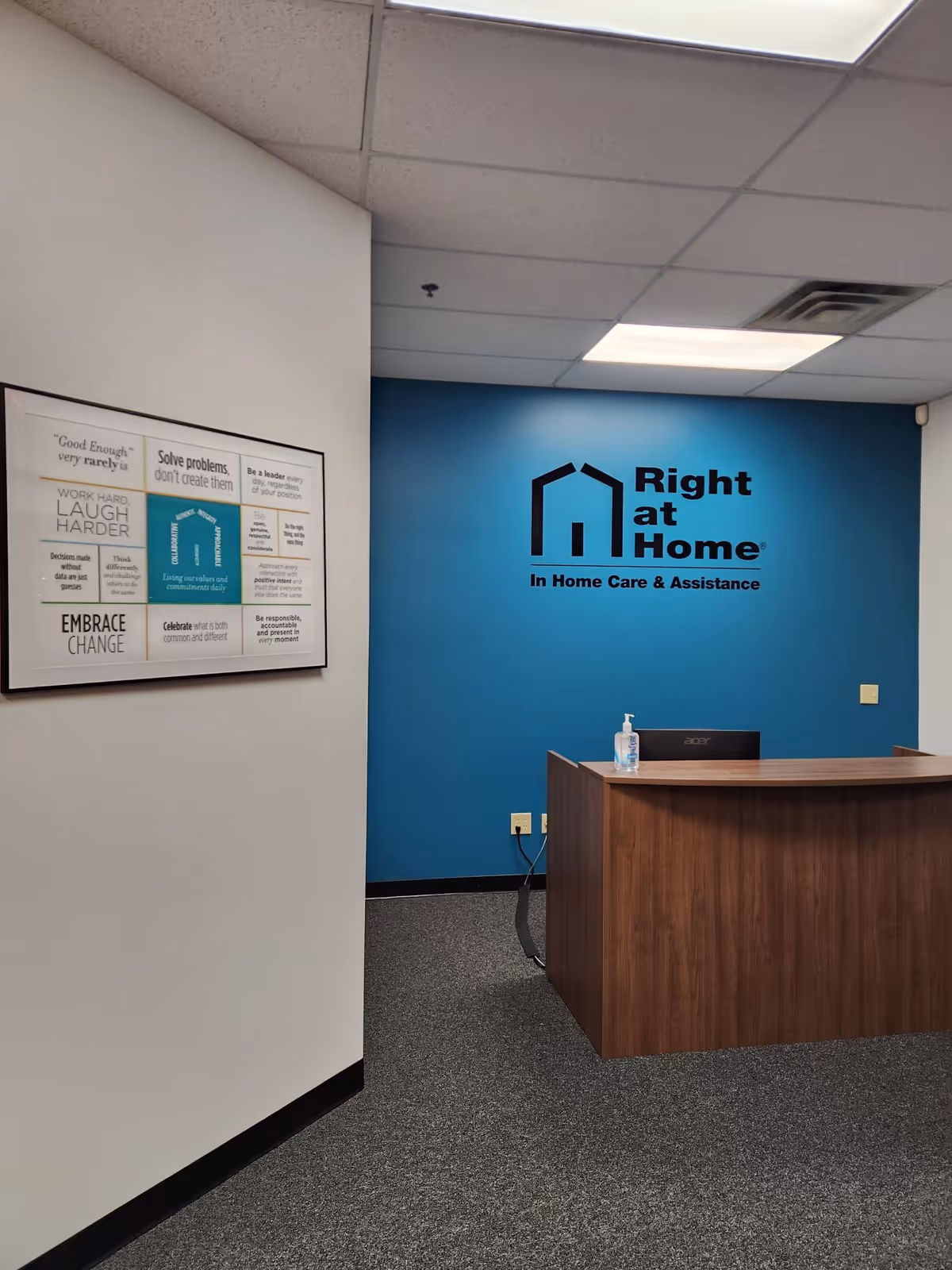 Reception desk in a blue-walled lobby displaying Right at Home logo and sanitizer.