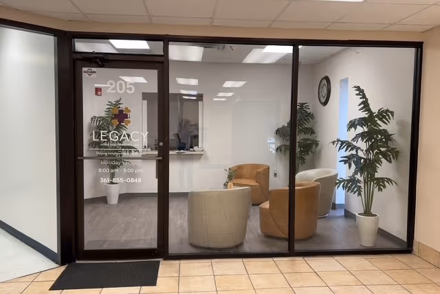 Glass entry to Legacy Home Health Agency lobby with seating area and potted plants.