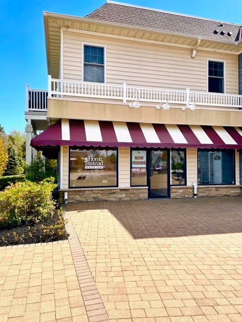 Two-story building exterior with maroon-and-white striped awning and storefront windows showing Home Instead.