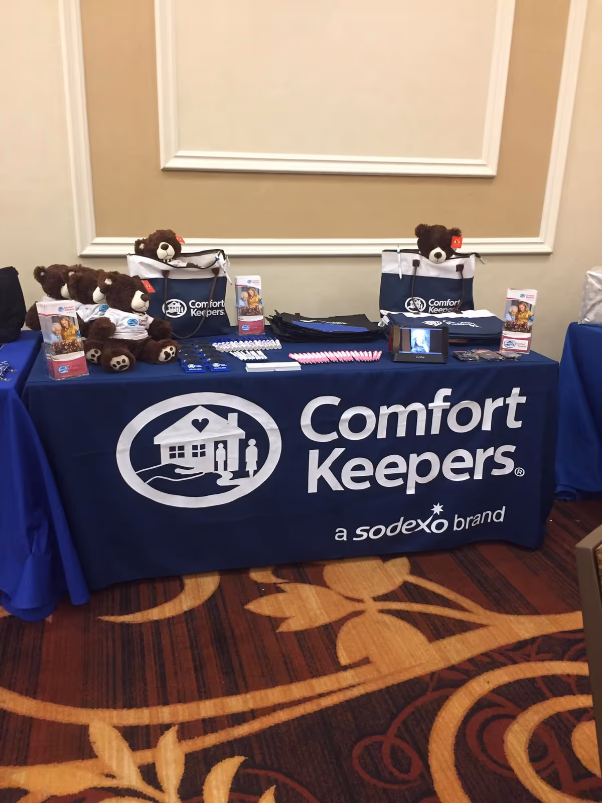 Indoor conference table displaying Comfort Keepers promotional materials with teddy bears and brochures.