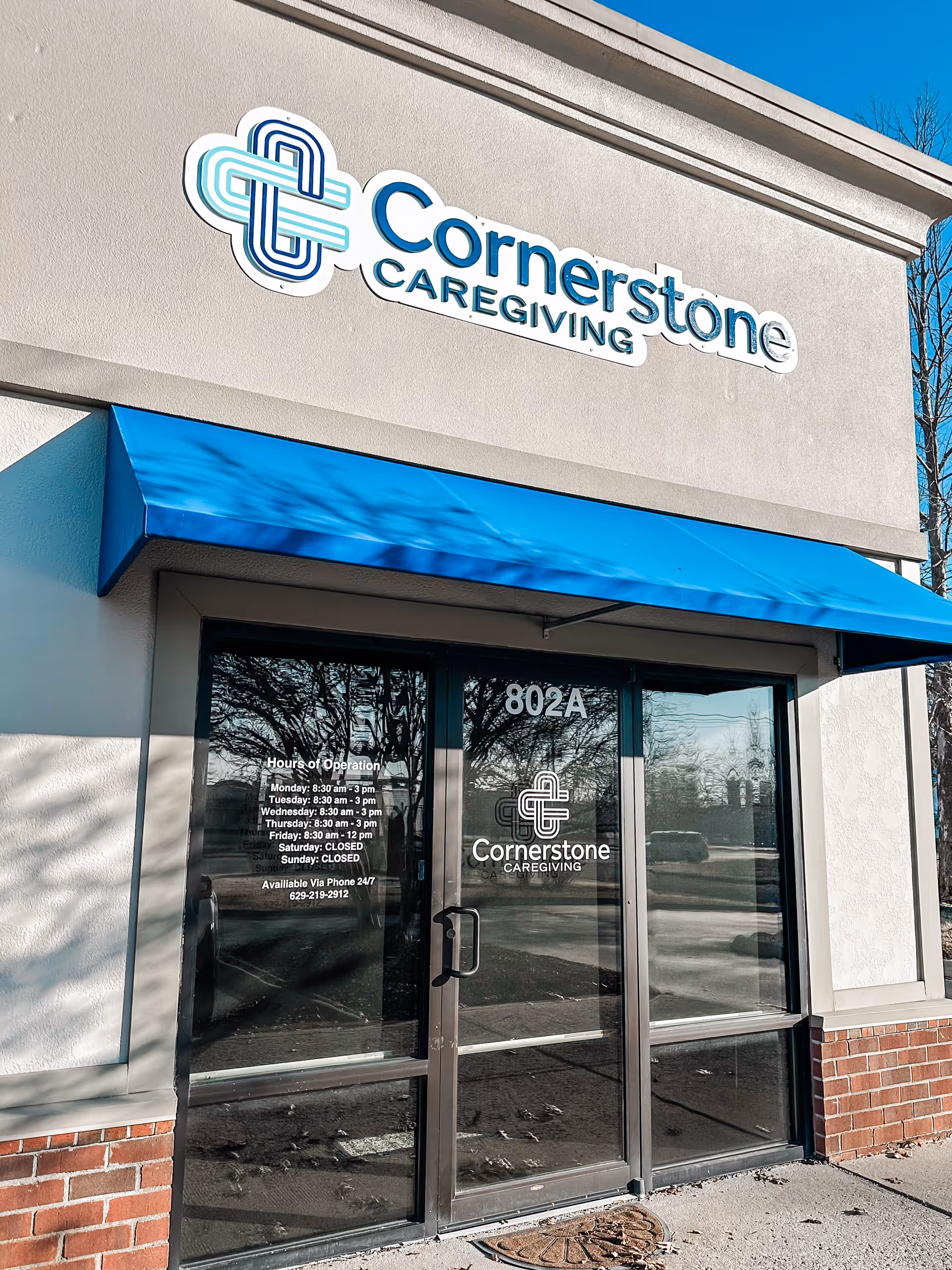Front of Cornerstone Caregiving building with blue awning and glass doors.