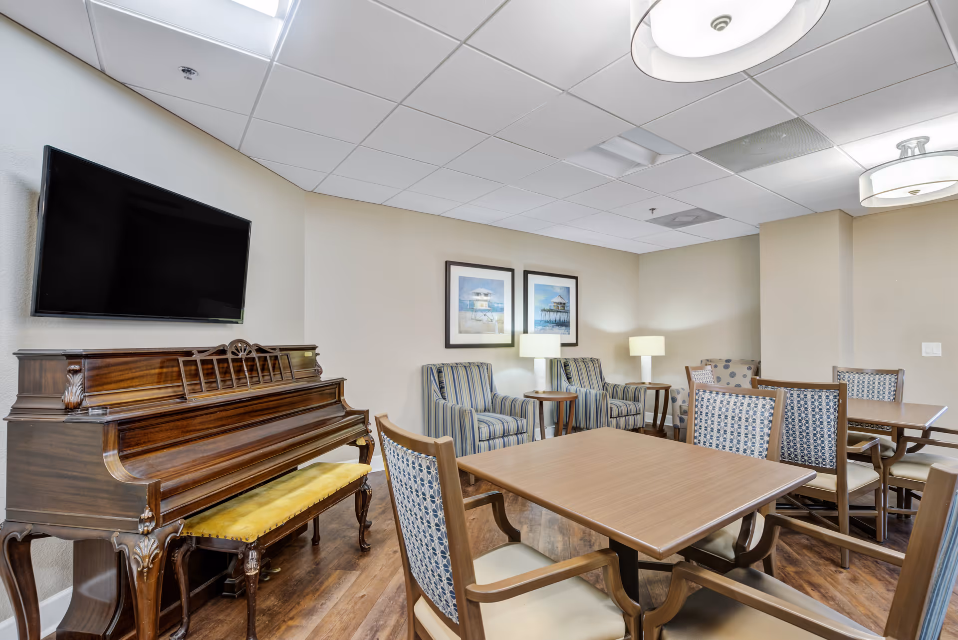 Cozy senior living common area with a piano, tables, and striped chairs.
