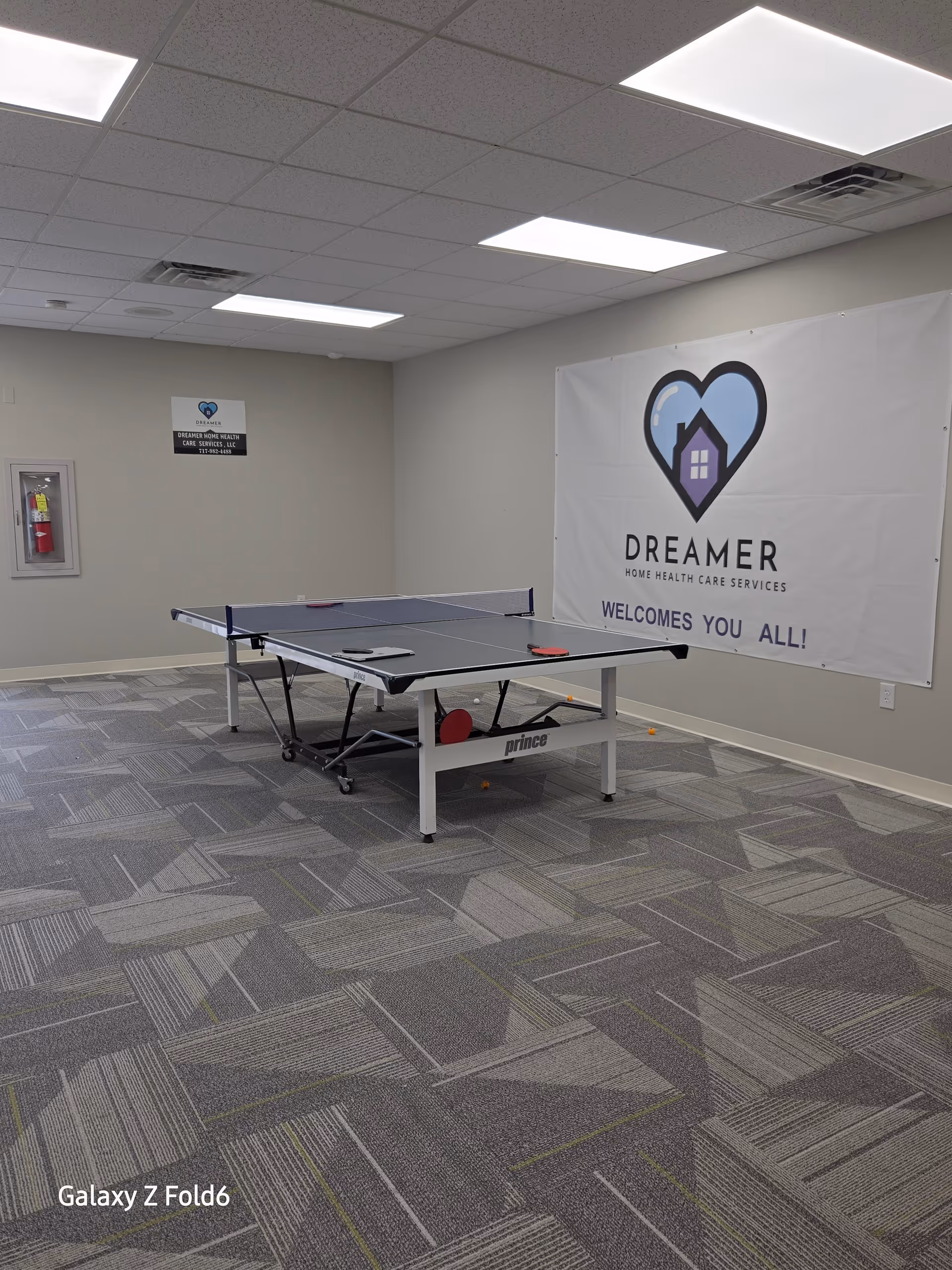 Indoor recreation room with a ping-pong table and a Dreamer banner.