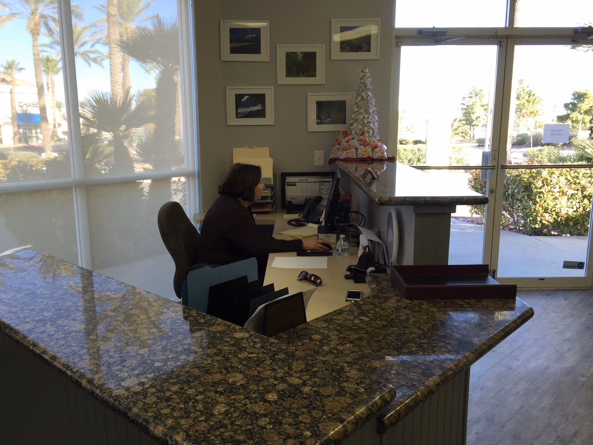 Reception desk with granite counters and staff at computer inside bright lobby.