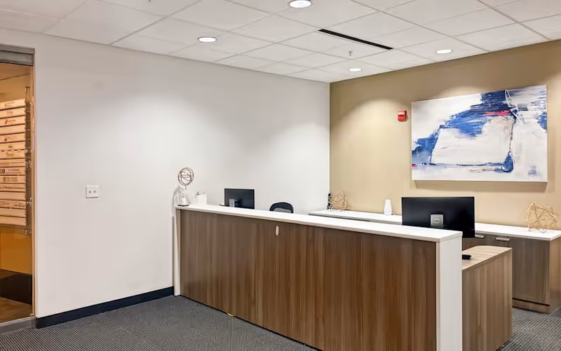 Interior reception area with a long wooden front desk and wall art