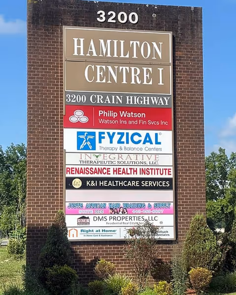 Tall brick signpost listing multiple businesses, including Right at Home, on a front exterior.