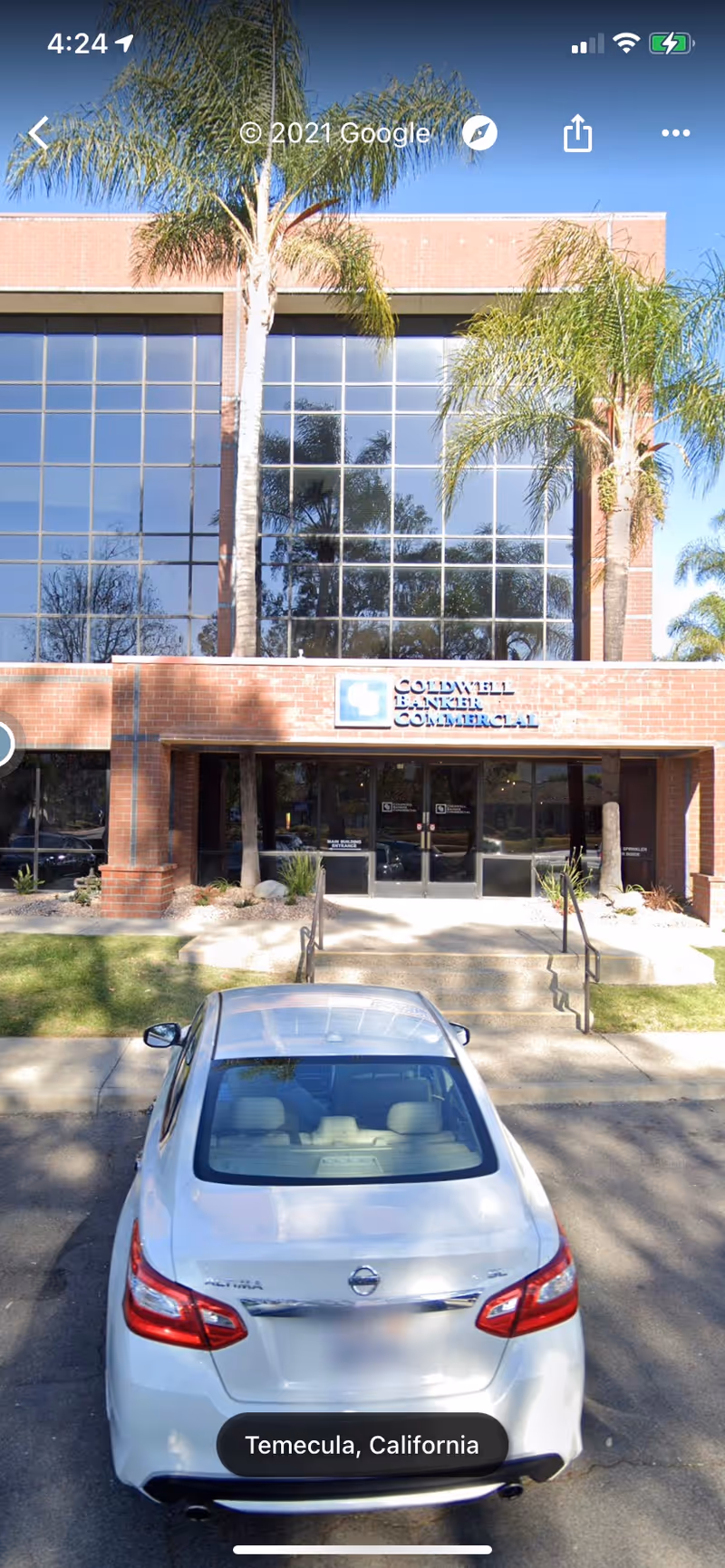 Exterior view of Amada Senior Care building with palm trees and a parked silver car.