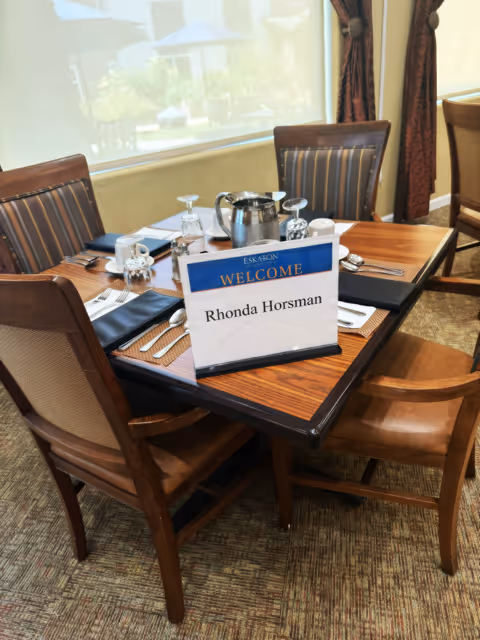 A senior dining room table set with a welcome sign and place settings.