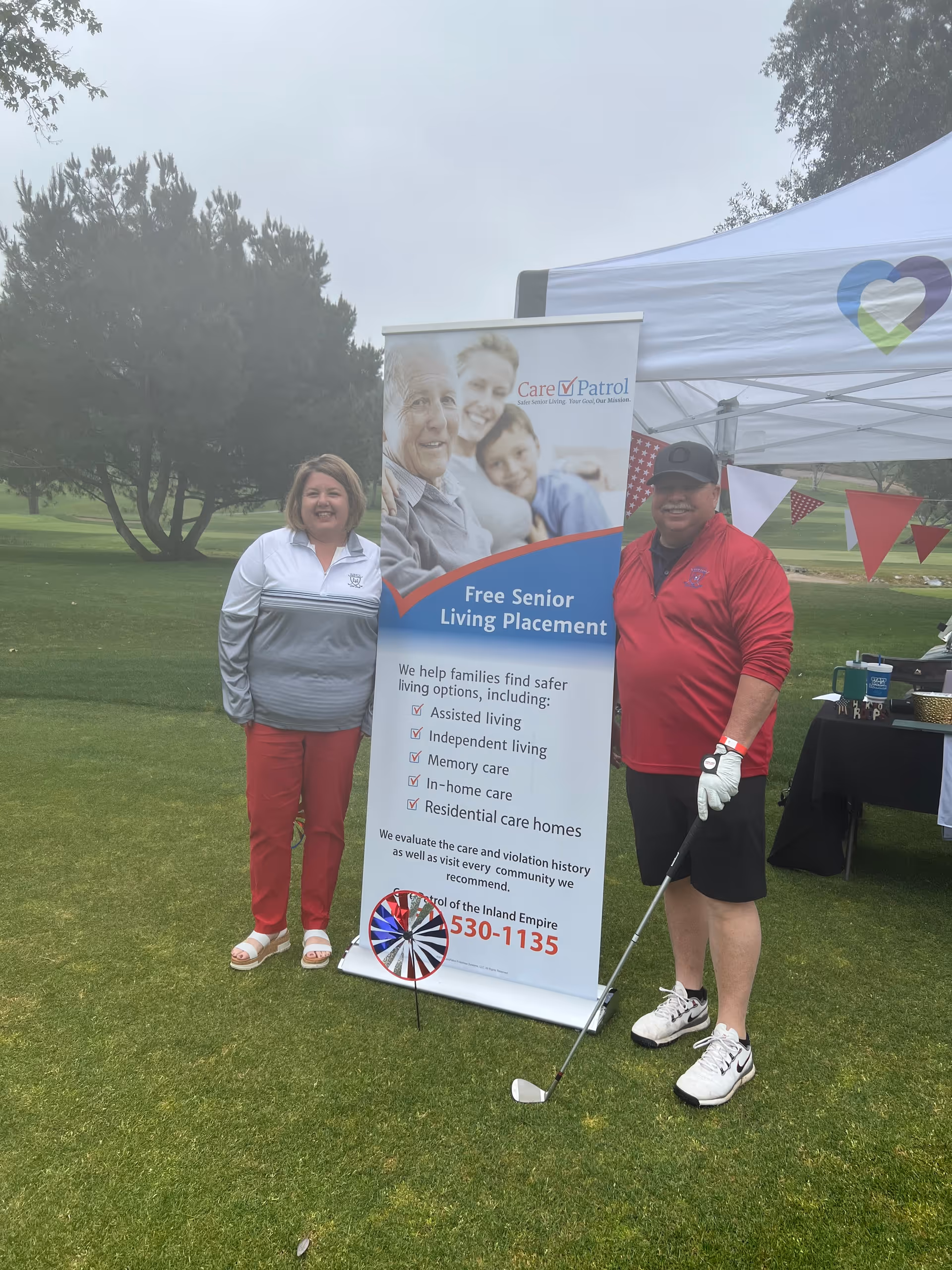 Two people stand beside a CarePatrol banner at an outdoor event.