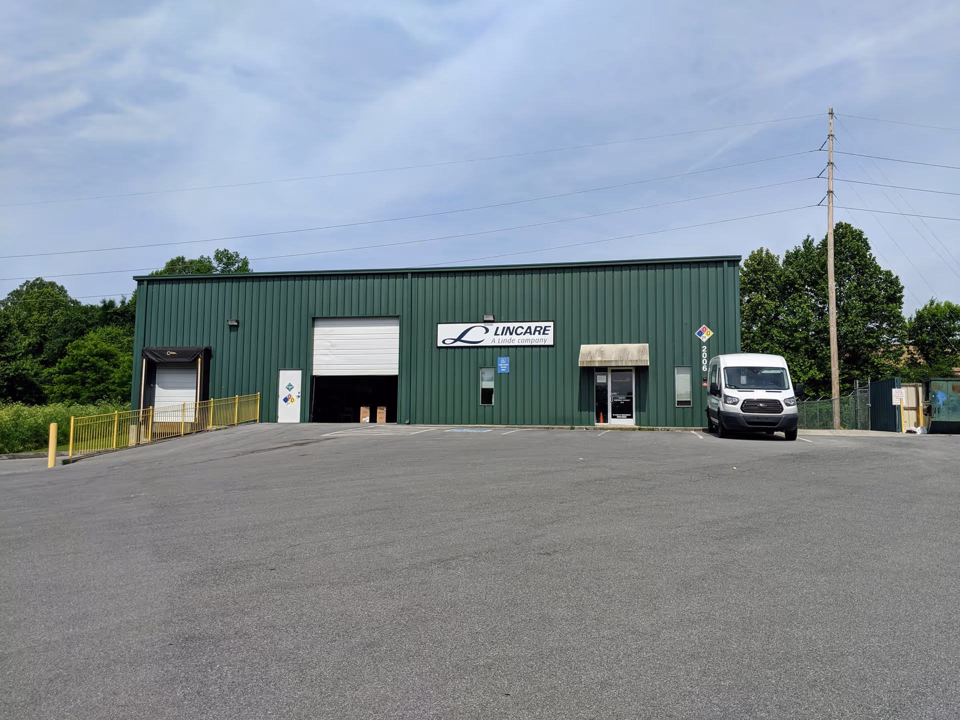 Green industrial building with a LINCARE sign, loading dock, and a white van outside.