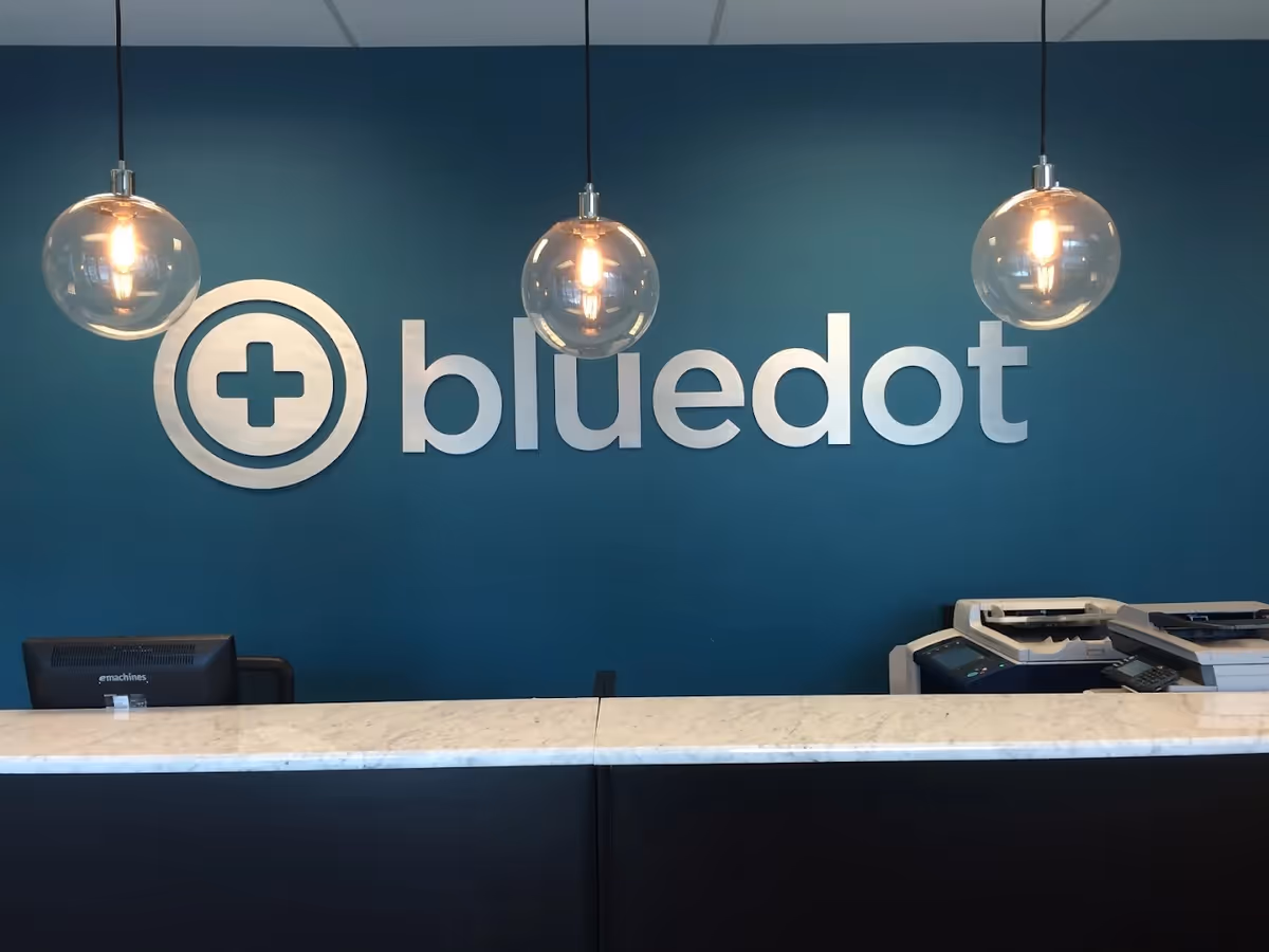 Reception area with blue wall, large bluedot logo, and marble counter.