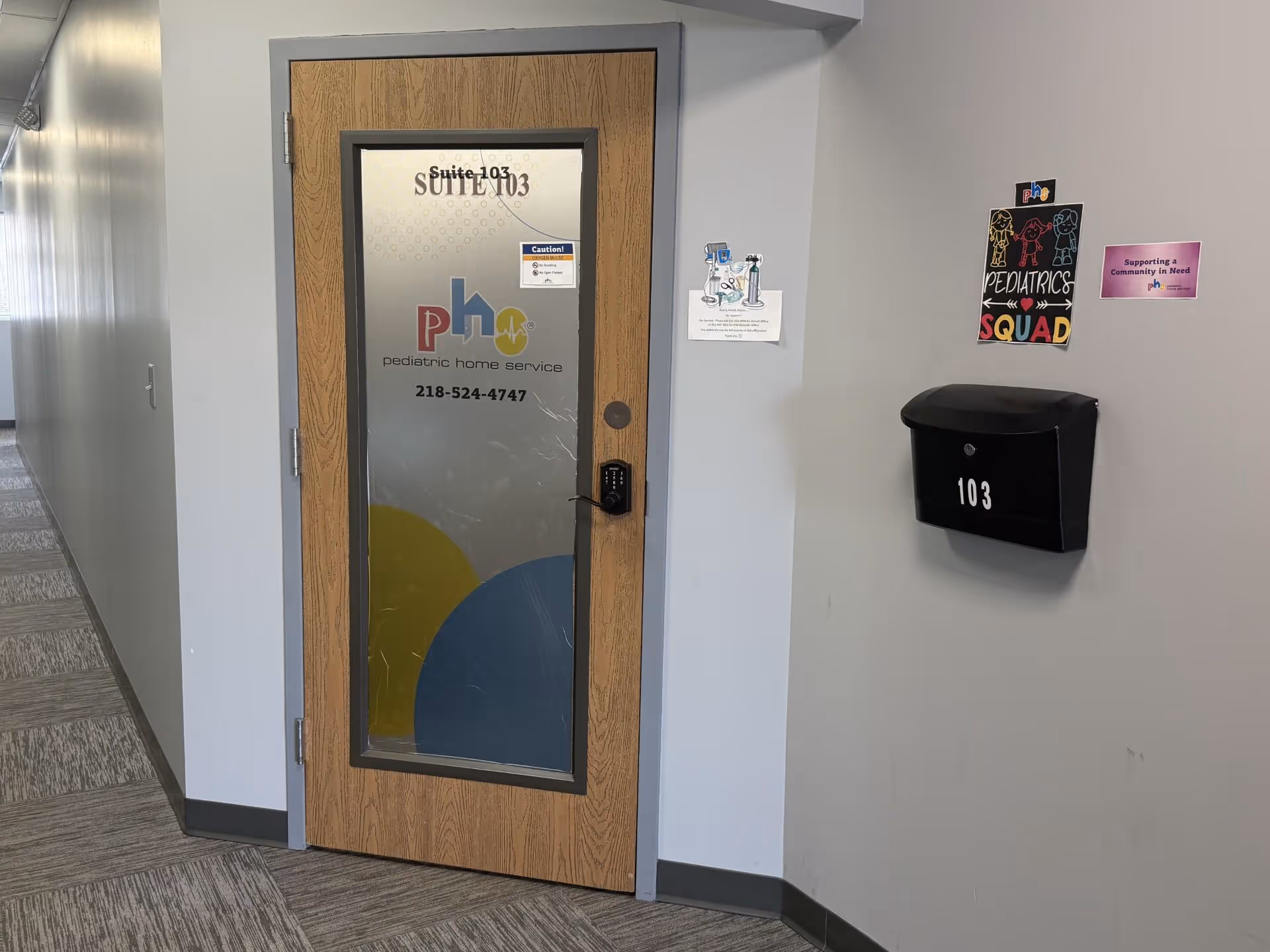 Wood-framed glass door labeled Suite 103 in a hallway with a wall mailbox