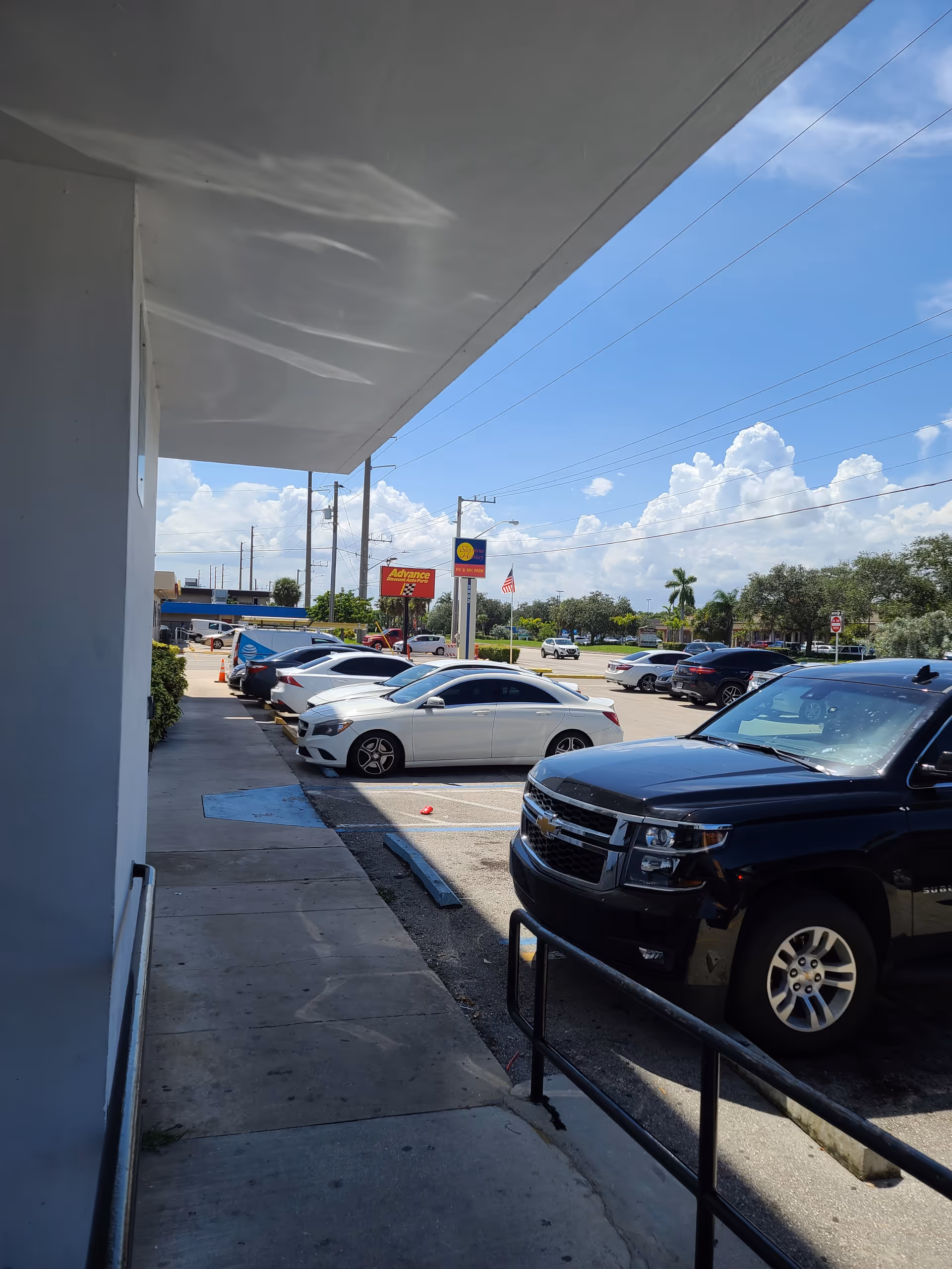 Exterior view of ASZ Caring Hearts Inc. facility with parked cars and blue sky.