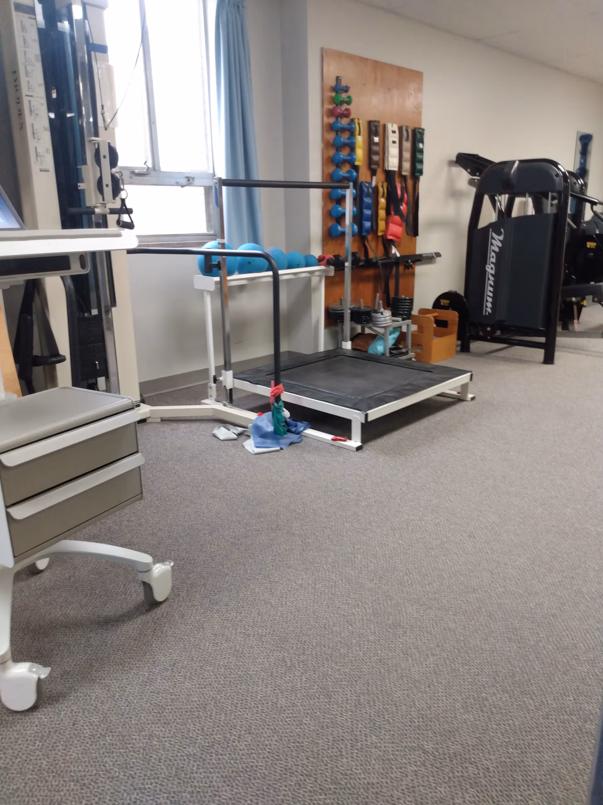 Indoor gym area with treadmill, weights, and exercise equipment in a senior facility.