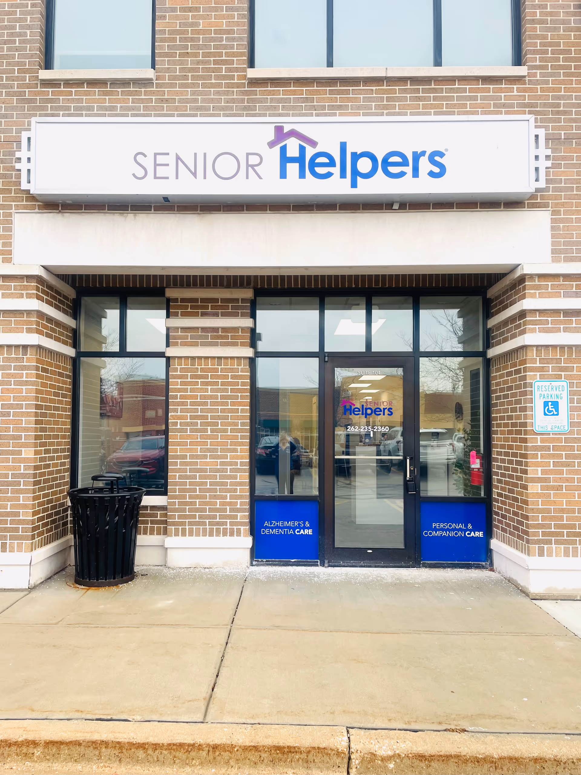 Exterior view of a Senior Helpers storefront with brick facade and glass doors.