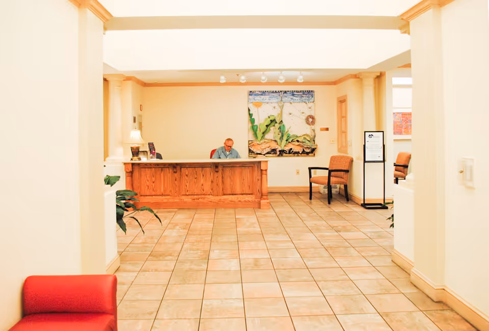 Bright interior lobby featuring a wooden reception desk, seating area, and artwork.
