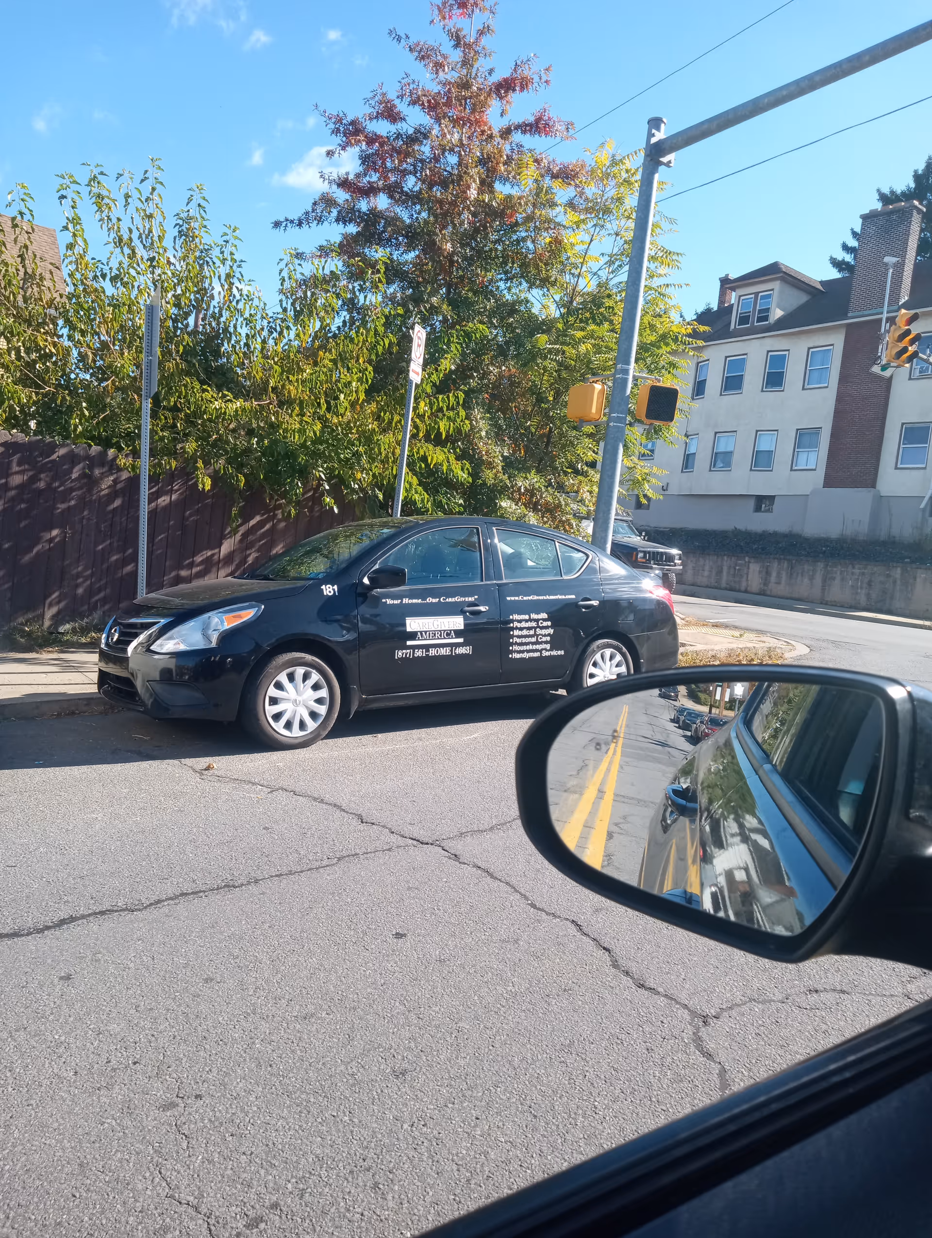 Black CareGivers America vehicle parked on street by building