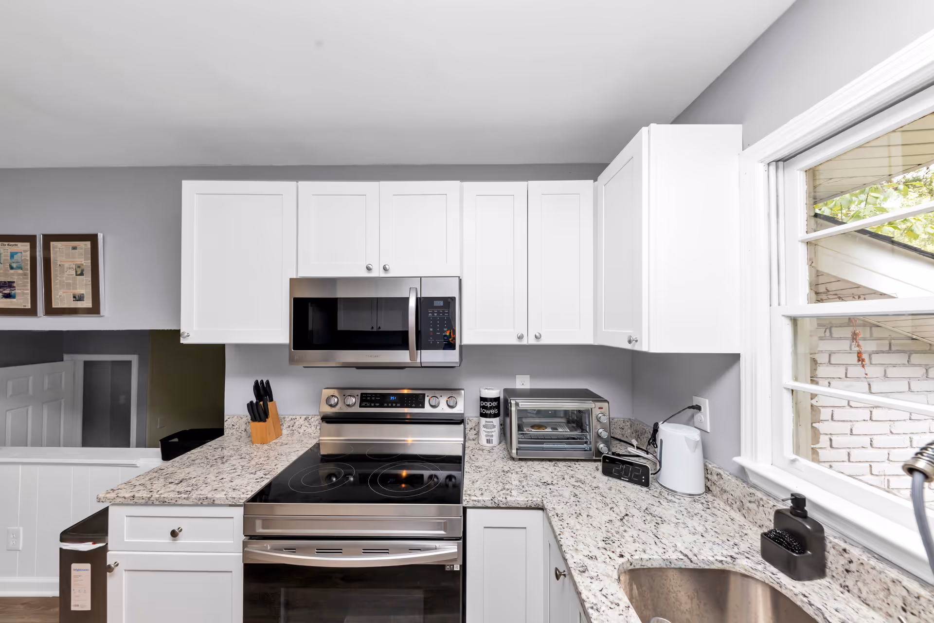 White kitchen with granite countertops, stainless appliances, and a bright window over the sink.