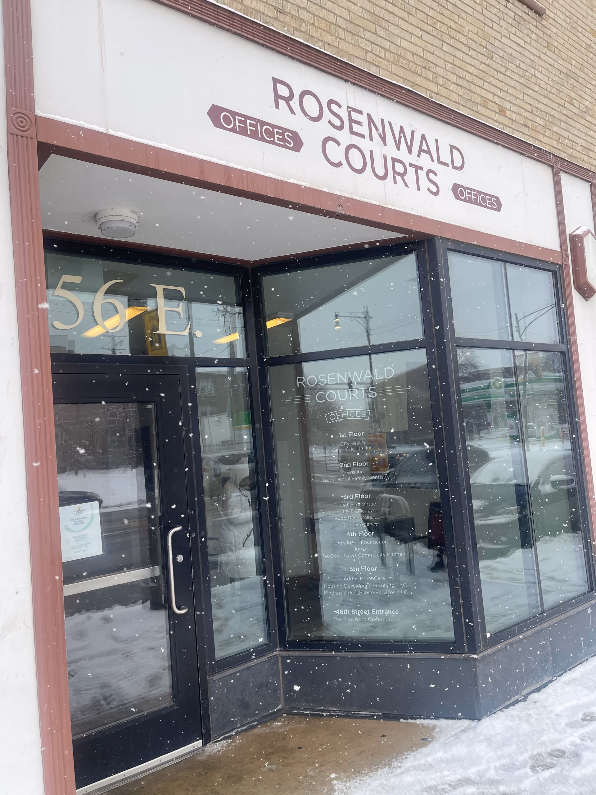 Exterior view of a building entrance with glass doors and Rosenwald Courts signage.