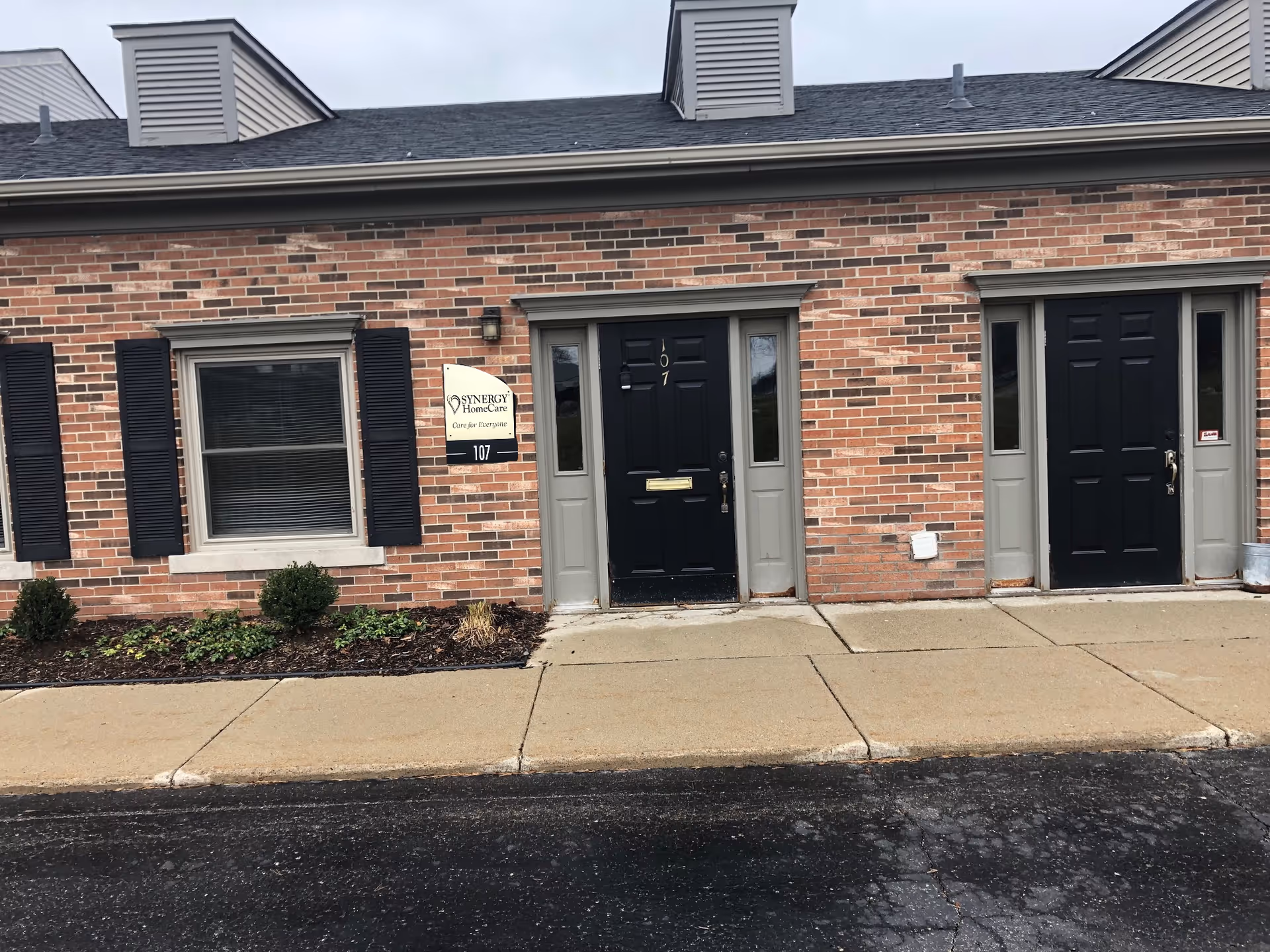 Brick exterior of a senior care facility with doors, windows, and a SYNERGY HomeCare sign.
