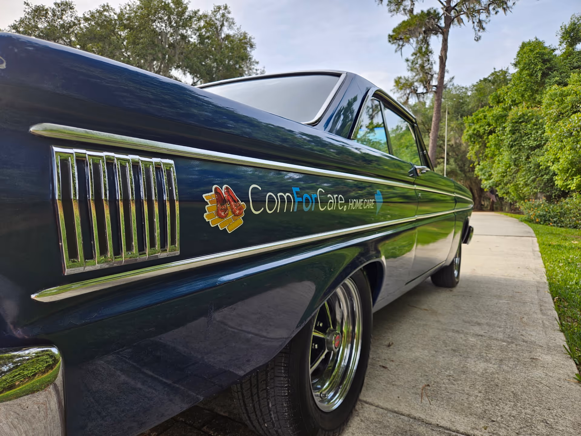 Side view of a dark blue vintage car with ComForCare Home Care logo.