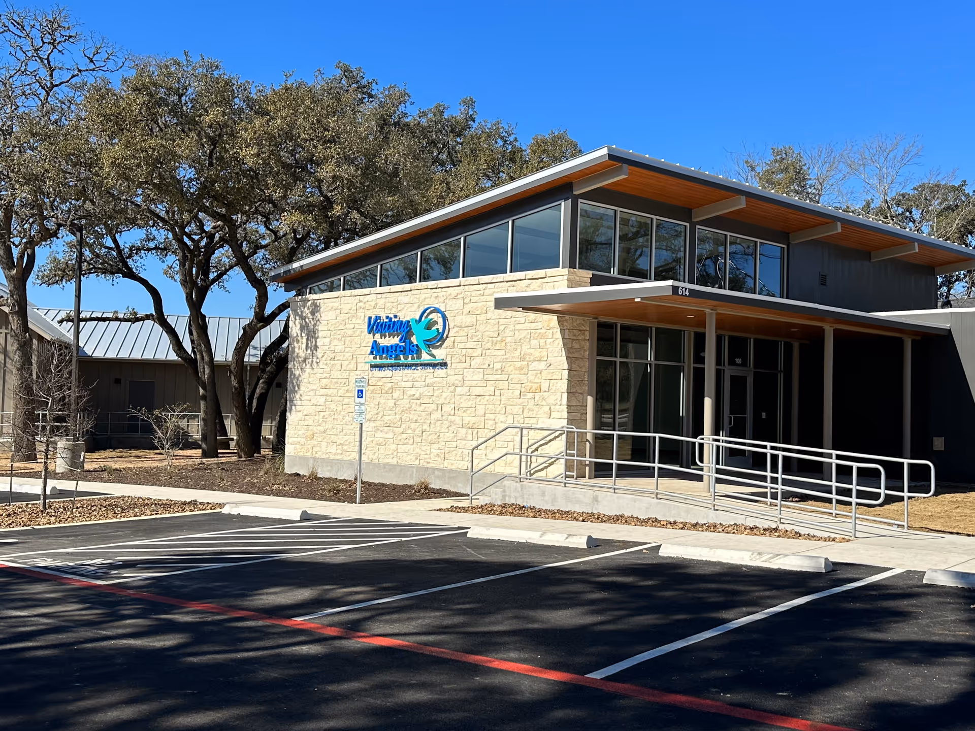 Exterior view of Visiting Angels Senior Home Care building with entrance ramp and parking.