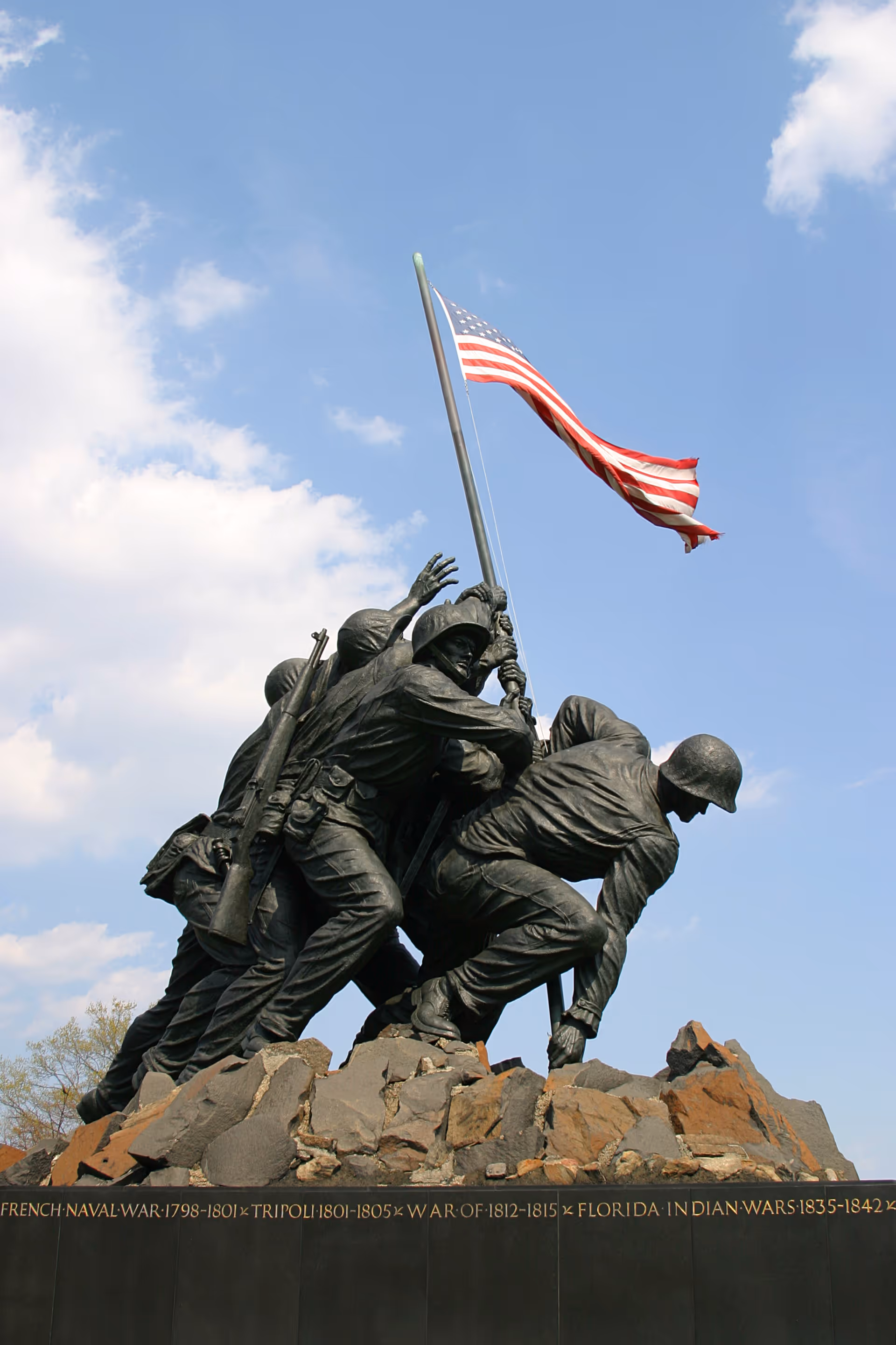 Bronze soldiers lift an American flag atop a rocky outdoor memorial.