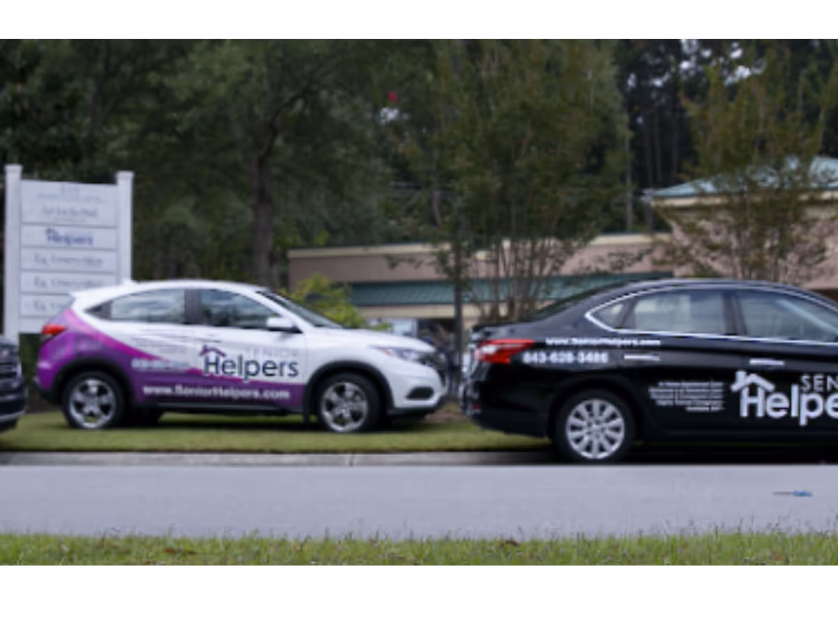 Two branded Senior Helpers vehicles parked outside a building along a street