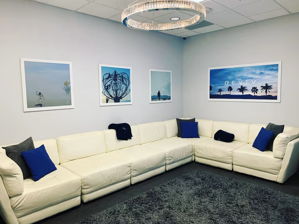 White sectional sofa arranged around a gray rug in a modern lounge with wall art.