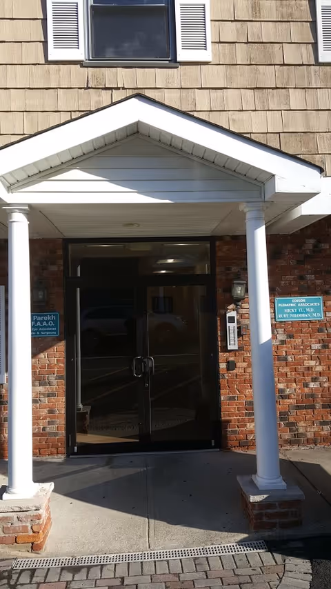 Brick building entrance with glass doors under a white portico and two columns