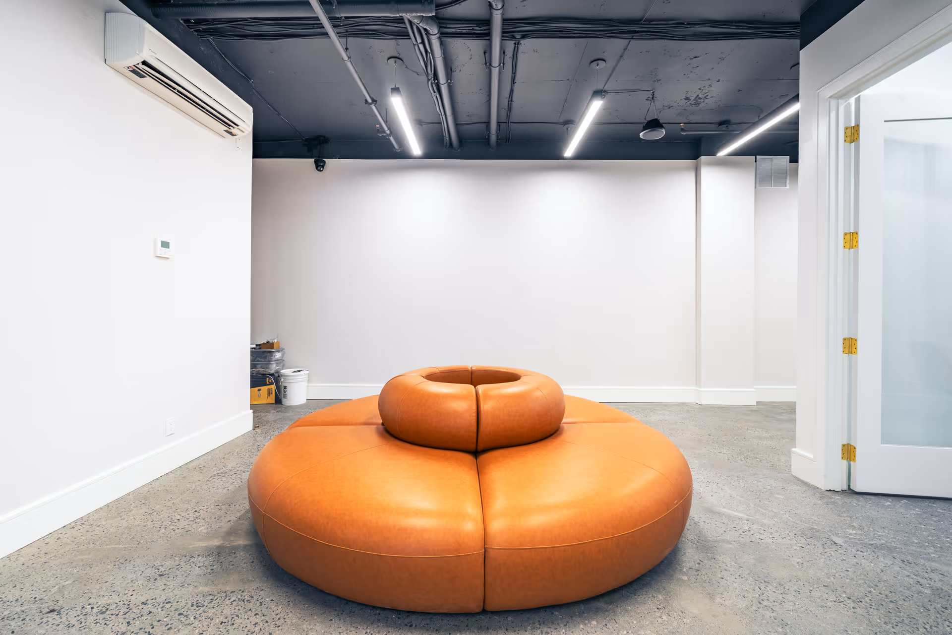 Empty modern lounge with large orange circular seating and white walls.