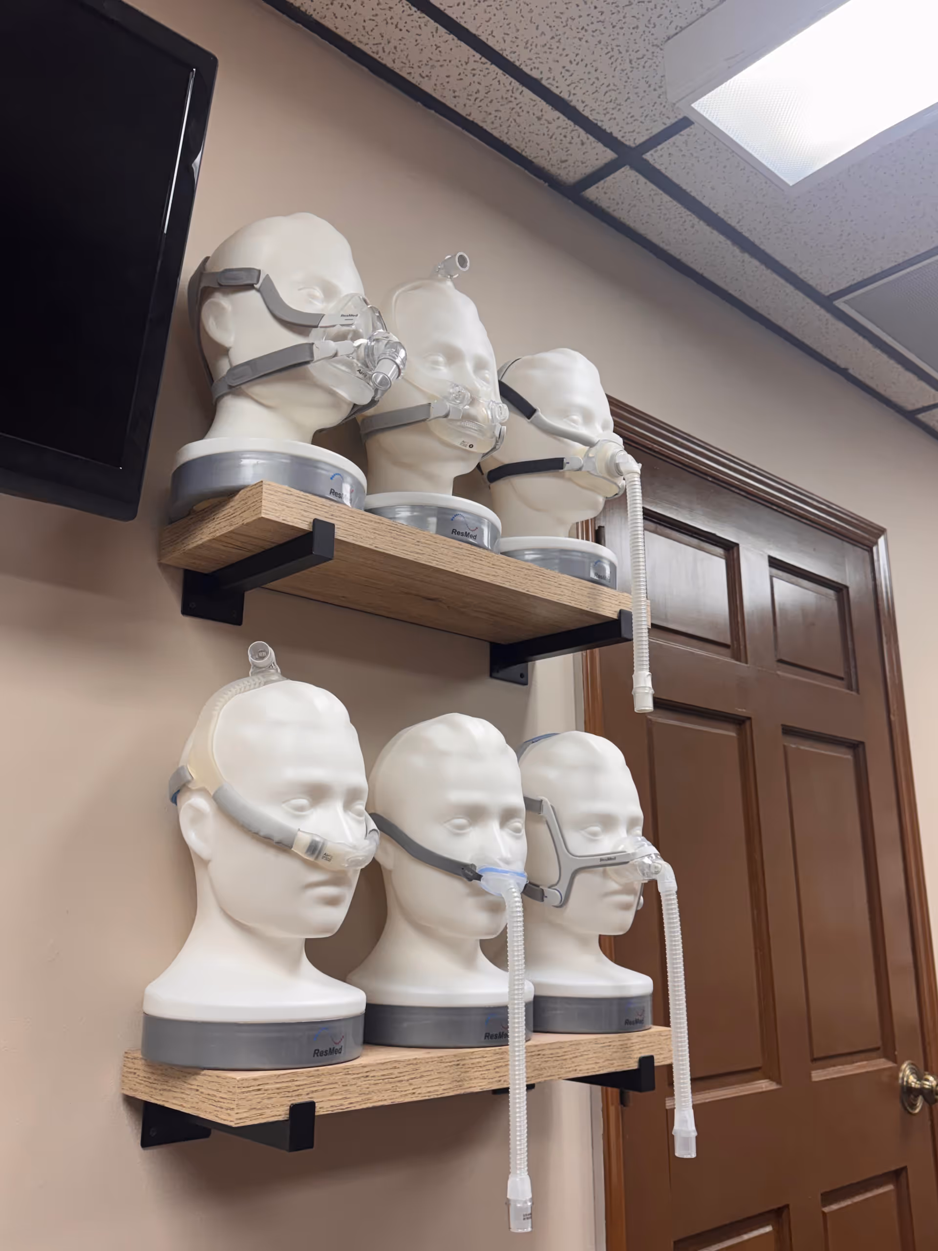 CPAP masks and hoses displayed on mannequin heads along wall shelves