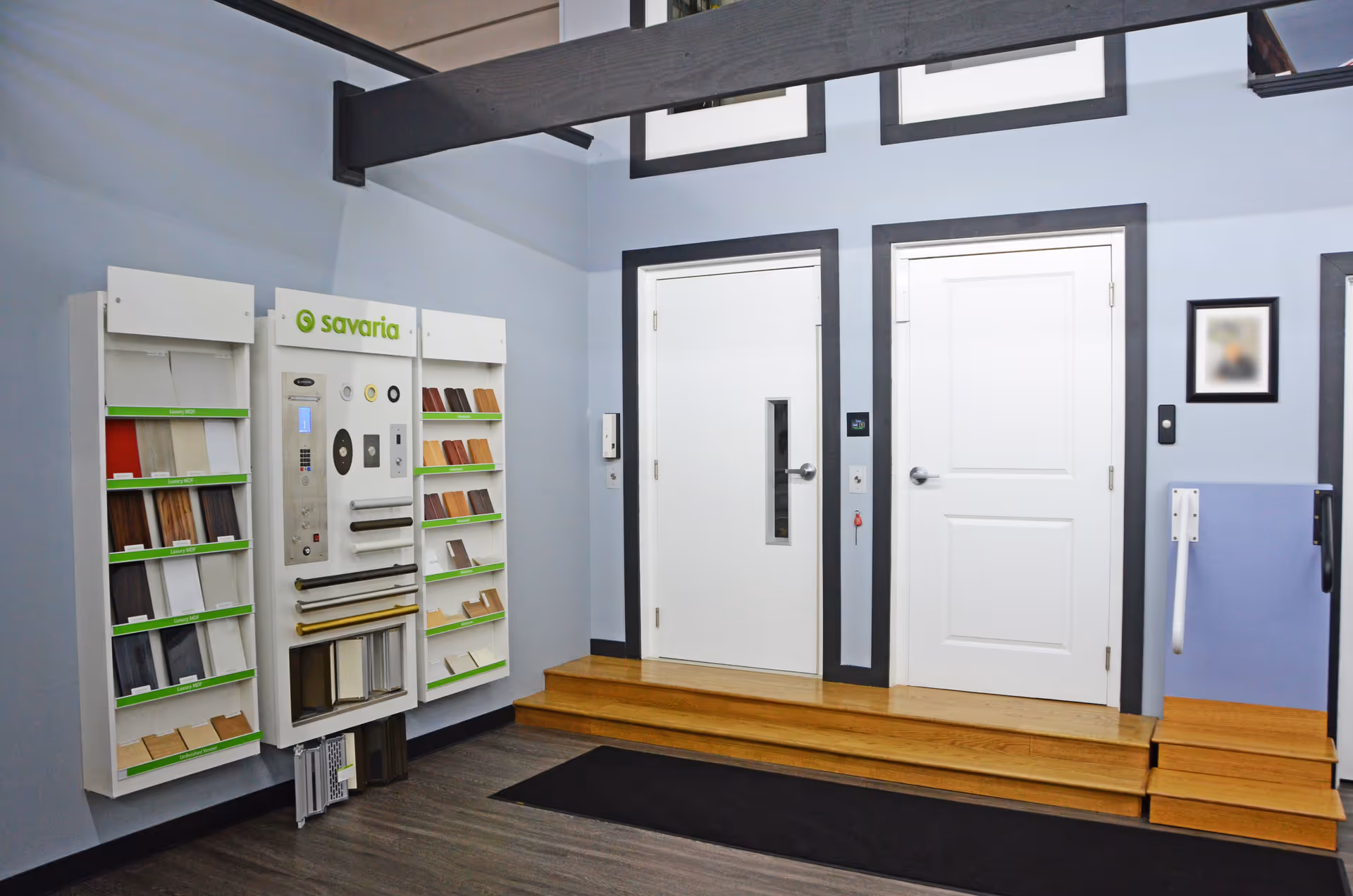 Interior showroom with two white doors, wooden steps, and flooring samples on display.