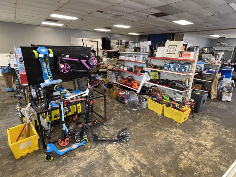 Indoor storage area at a facility with shelves, scooters, and assorted equipment.