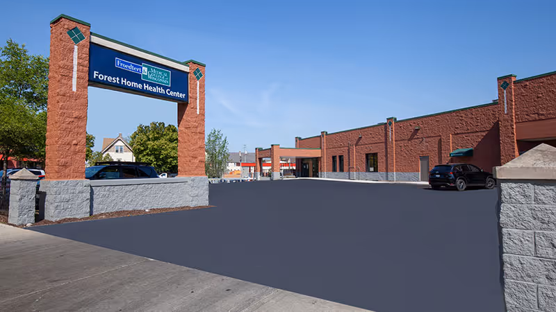 Exterior view of Forest Home Health Center with brick buildings and a paved driveway.