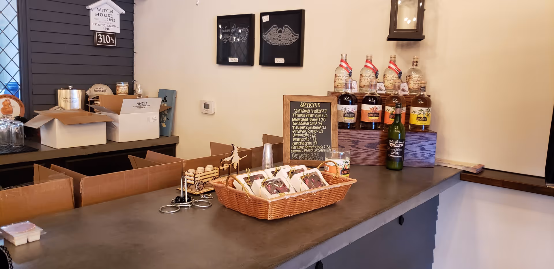 Indoor reception area with a counter bar, bottled spirits, a chalkboard menu, and baskets.
