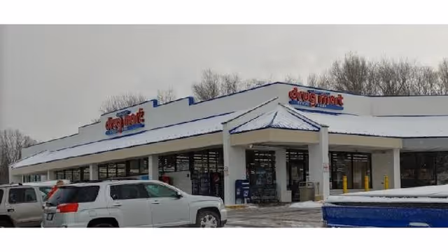 Exterior view of Discount Drug Mart storefront with snow-covered roof and parked cars.
