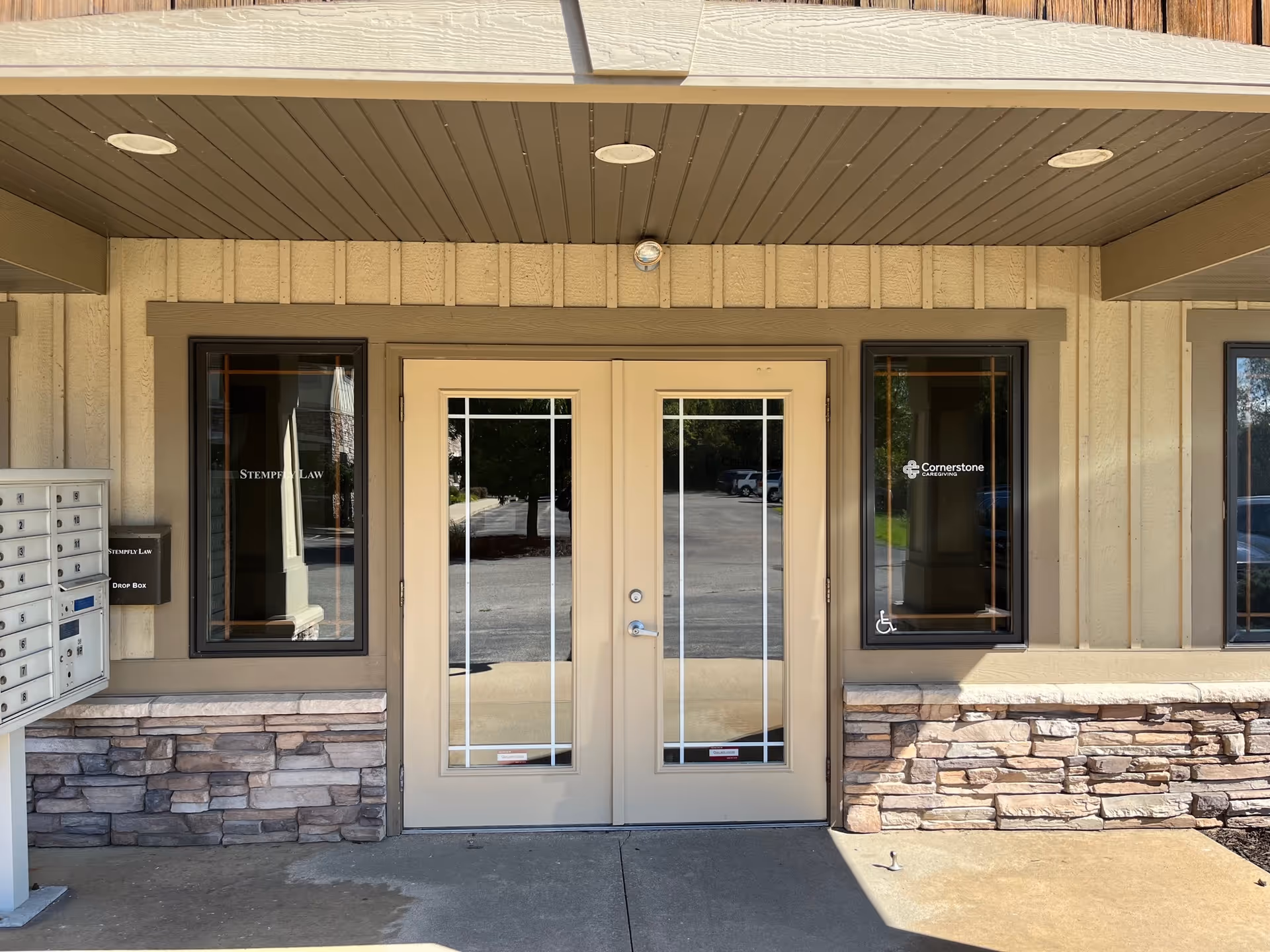 Exterior entrance of Cornerstone Caregiving building with double glass doors and stone facade.