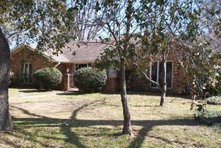 A single-story brick facility with a front yard and trees.