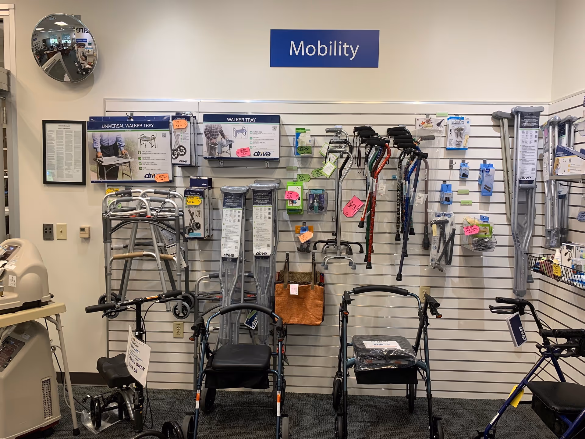 Mobility equipment display with walkers, canes, and crutches on a slat wall.