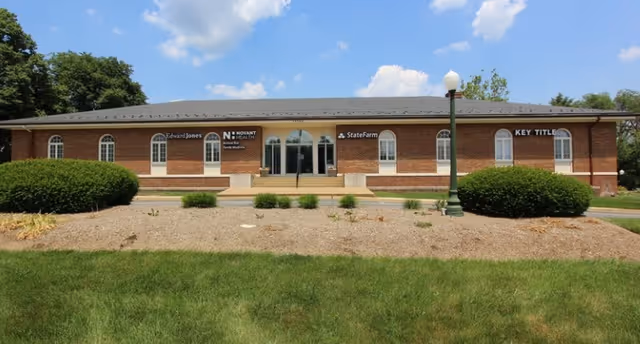 Brick facility building with arched windows and a central entrance, landscaping in front.