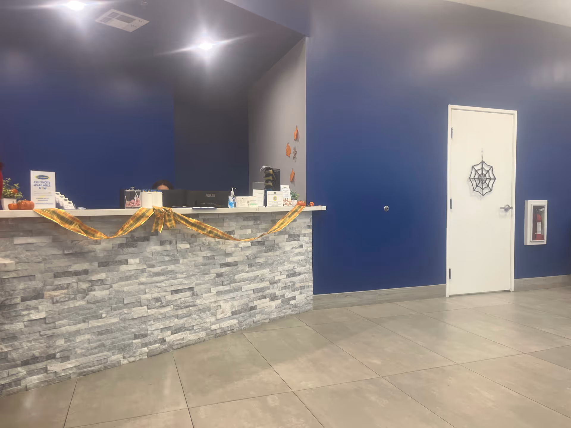 Blue-walled lobby with a stone-front reception desk and Halloween decorations.