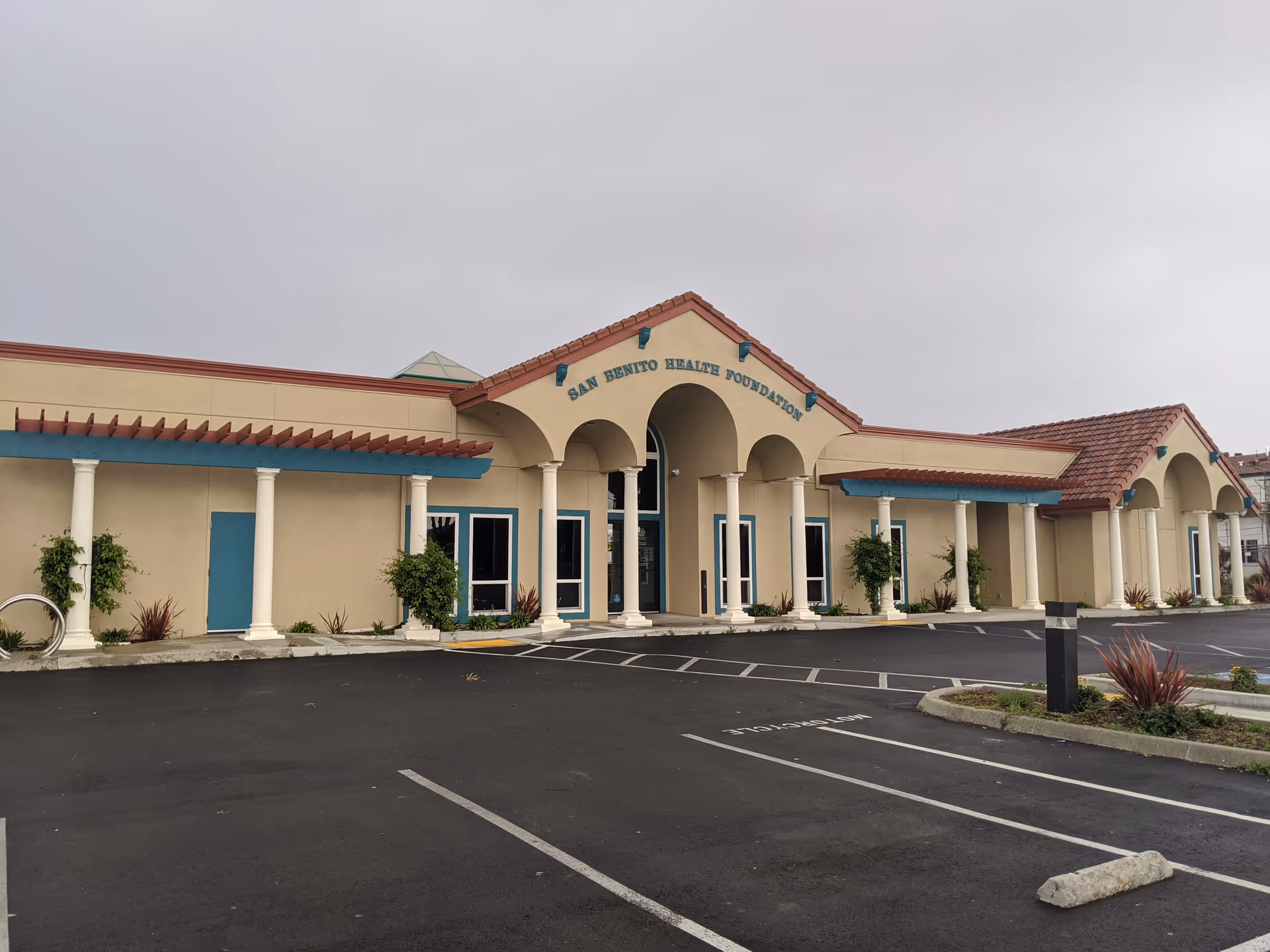 Exterior view of a single-story senior living building with arches and a parking lot.