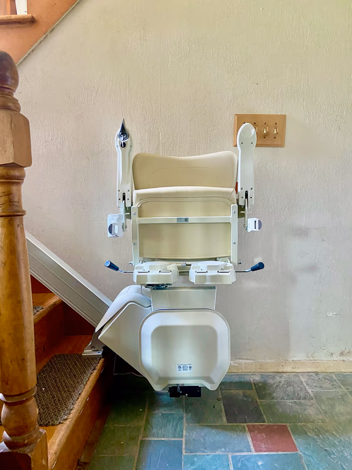 A stairlift chair mounted beside a staircase in an interior space.