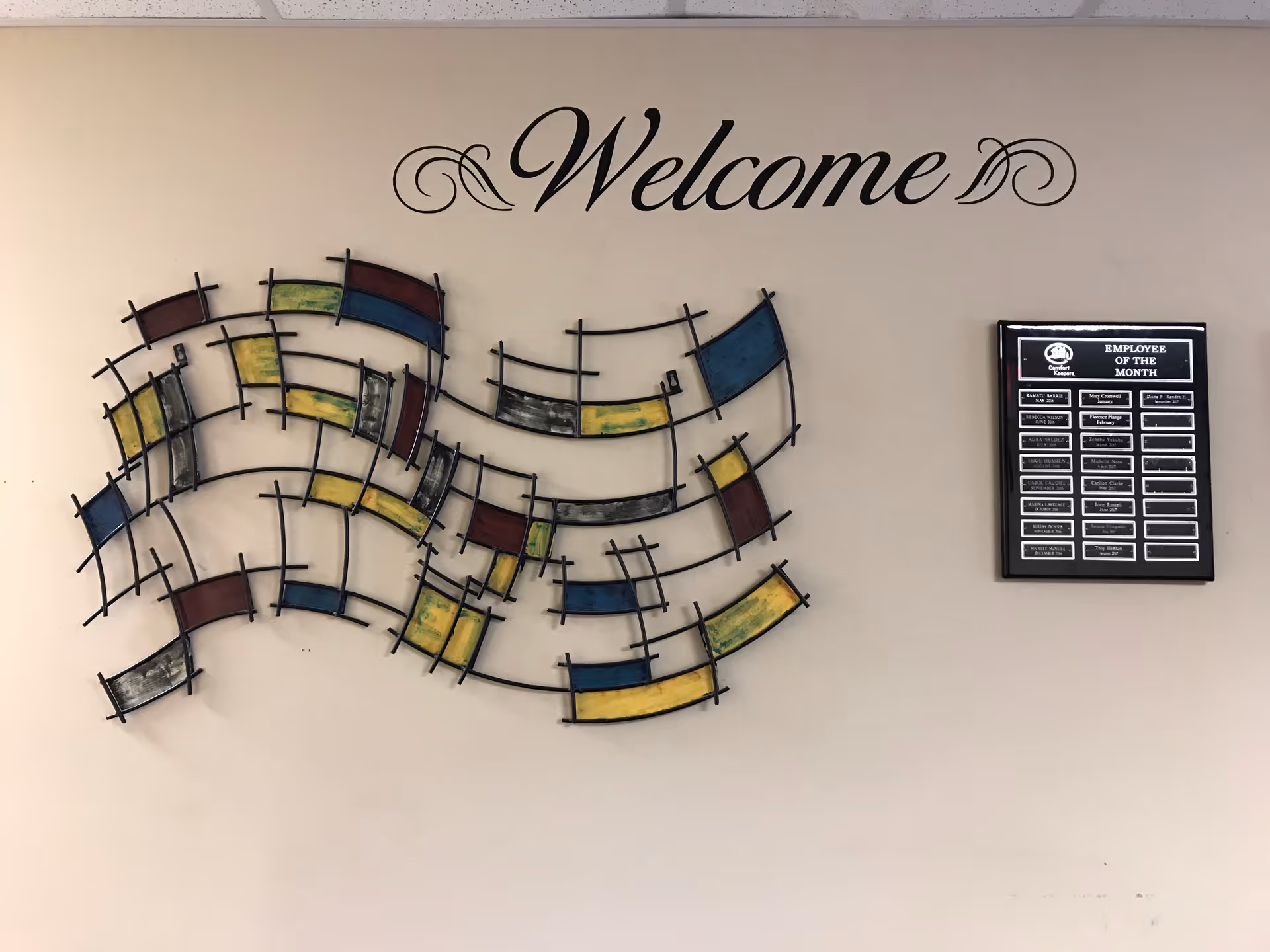 Beige wall featuring a 'Welcome' sign and colorful abstract metal wall art.