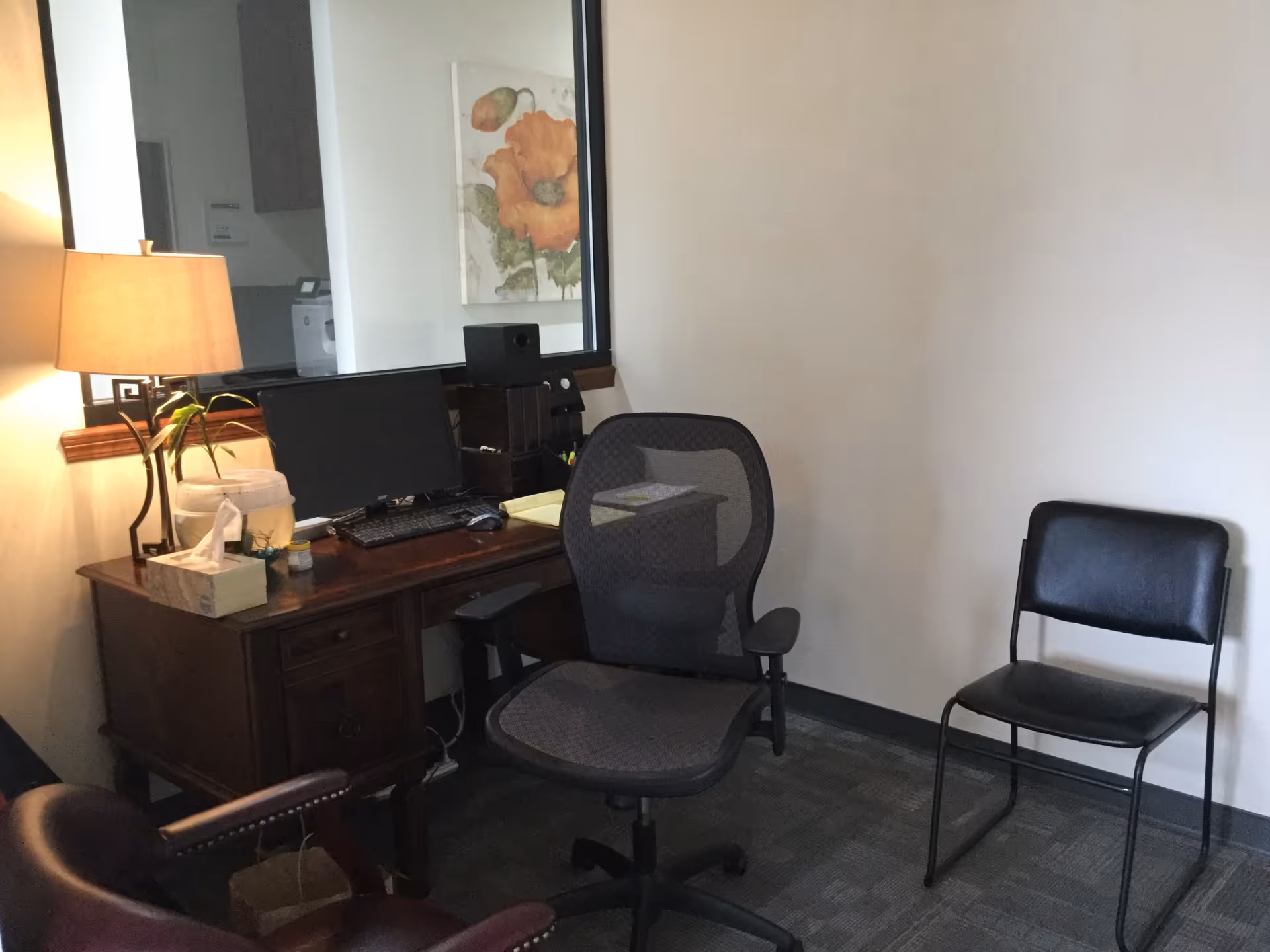 A small office area with desk, computer, lamp, and two chairs in a senior care facility.