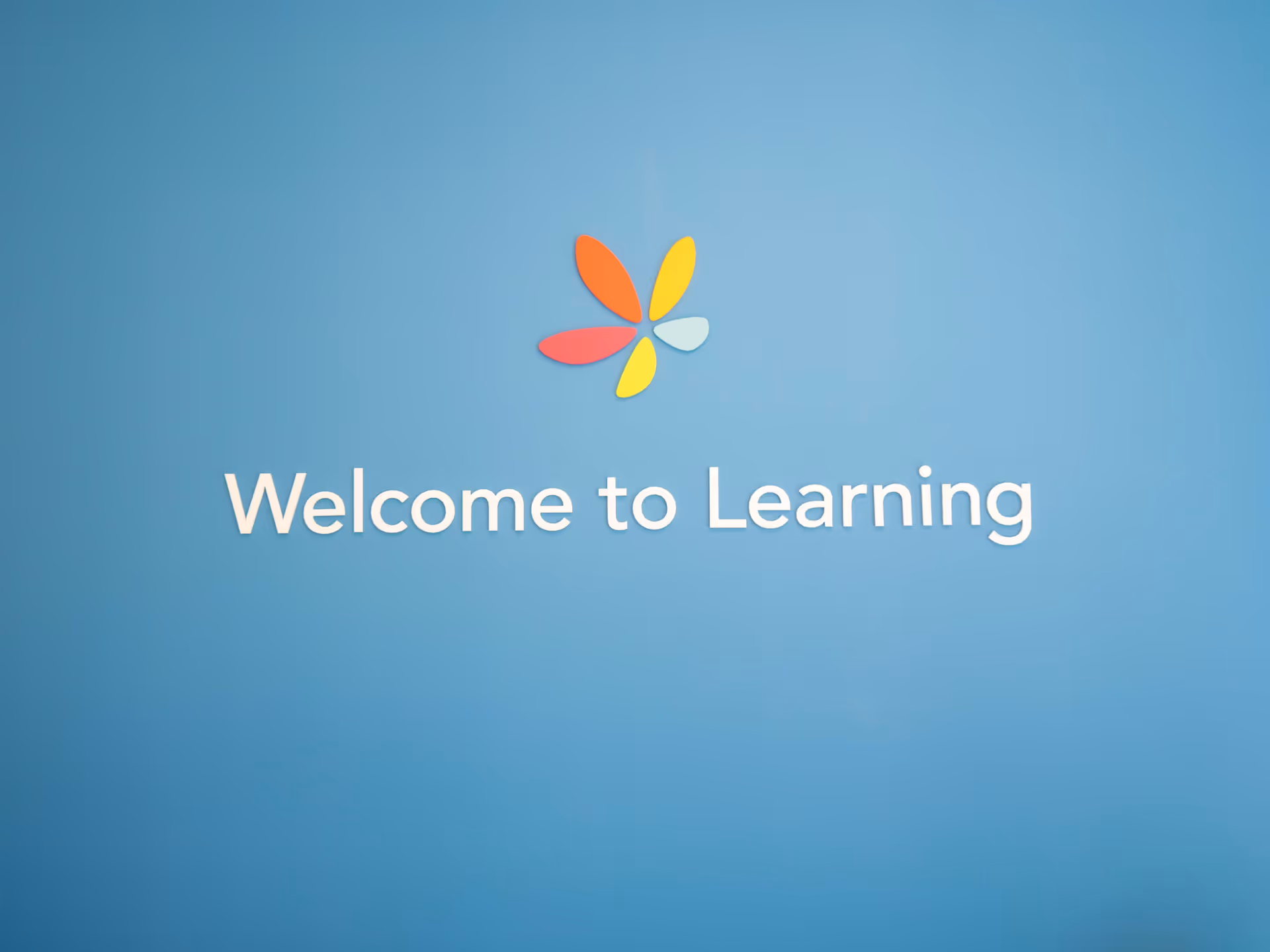 Blue wall with a colorful flower logo and the words Welcome to Learning.
