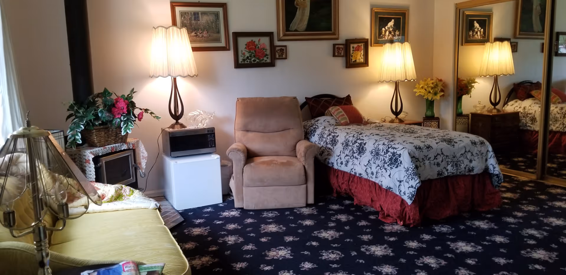 A cozy senior living bedroom with a floral bedspread, armchair, and lamps.