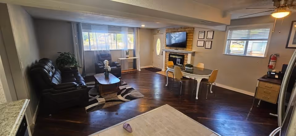 Cozy senior living area with leather sofas, a fireplace, TV, and a dining table.