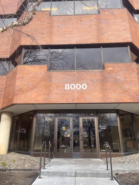Brick building entrance with large glass doors and the number 8000 on the facade.